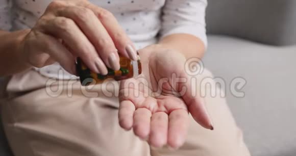 老妇人手里拿着胶囊从瓶子里倒药丸视频的预览图
