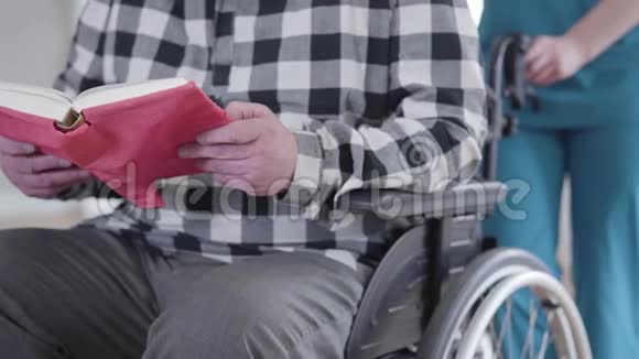 不可辨认的白种人老人坐在轮椅上读着蓝色的无效标书视频的预览图