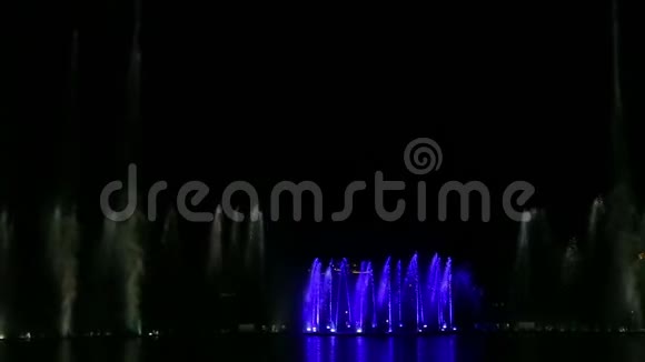 在水中倒影的夜空背景下喷泉呈现出五颜六色的明亮景象视频的预览图