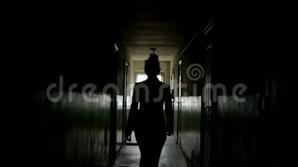 黑暗暴露的轮廓一个女人从后面的视线在离焦一个女人正沿着黑暗的走廊走着视频的预览图