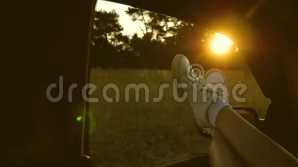 一个女孩的腿在车窗里阳光灿烂骑着一辆车在乡间的路上女人开车旅行年轻女子视频的预览图