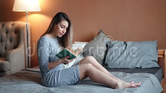 光脚家庭美女看书翻页坐在家里的床上视频的预览图