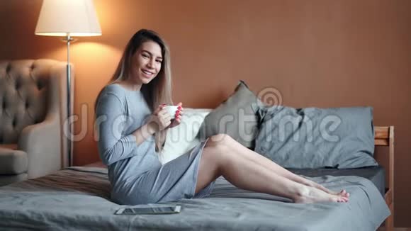 放松的家庭年轻女性在豪华的家里享受在床上喝茶的积极情绪视频的预览图