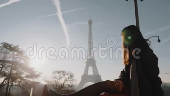 坐在巴黎埃菲尔铁塔围栏边的年轻旅游妇女在度假时微笑着慢镜头视频的预览图