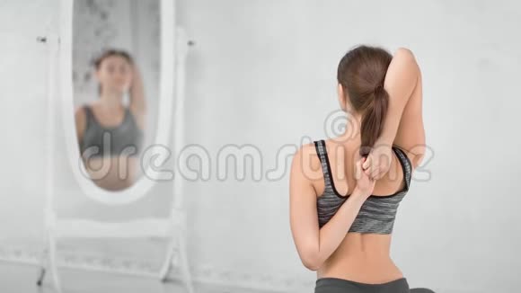 灵活的瑜伽女性手连在背后锻炼皮拉茨工作室后景视频的预览图