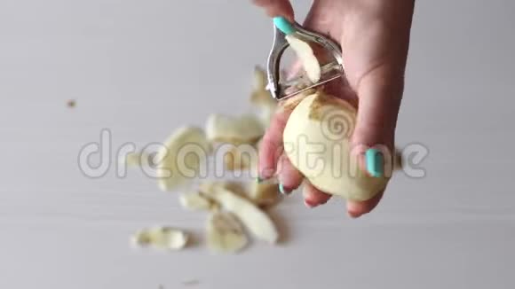 一个女人在厨房用削皮机剥土豆皮的特写镜头4K视频的预览图