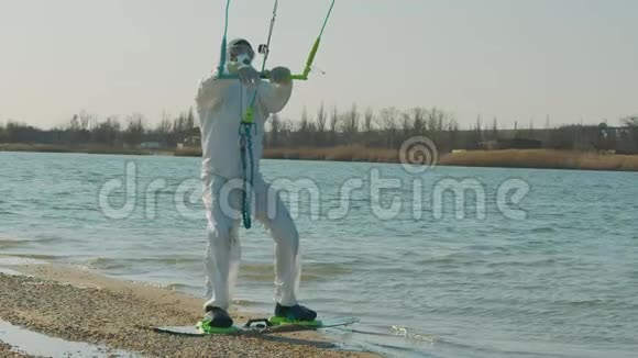 穿着医用个人防护装备的男子在海洋风筝冲浪极限夏季运动慢动作病毒视频的预览图