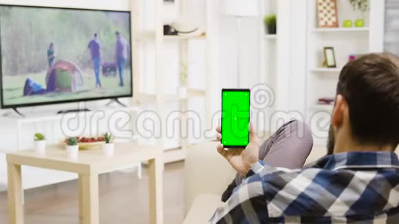 一名白人男子双手垂直握着一部绿屏手机视频的预览图