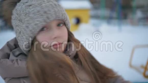在白雪皑皑的城市里戴着冬帽和夹克的开朗的女孩在四处张望合上幸福的脸笑的少年女孩视频的预览图