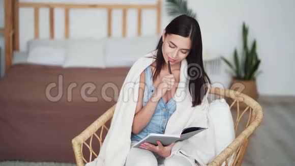 有格子的女人坐在椅子上看书手里拿着铅笔视频的预览图
