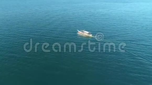 在菲律宾巴拉望日落时分一艘传统的班卡船漂浮在开阔的海洋中视频的预览图
