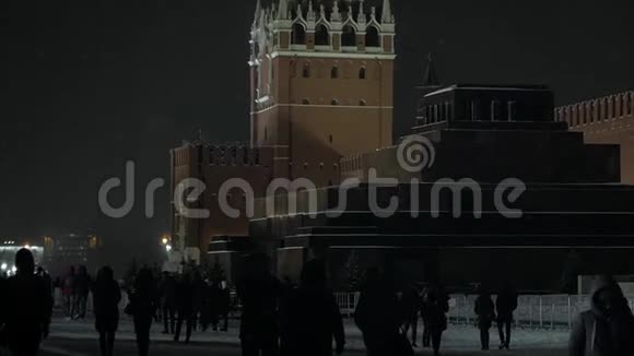 红色广场与人的轮廓降雪期间的克里姆林宫陵墓和斯巴达塔视频的预览图
