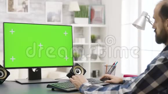 用绿色屏幕放大在电脑上工作的年轻人的视差镜头视频的预览图