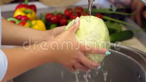 一个年轻女人在厨房的水槽里洗新鲜的卷心菜4K视频的预览图