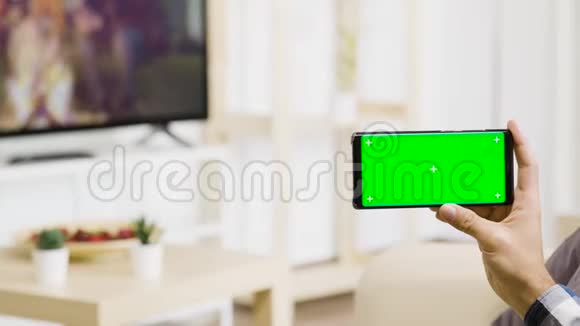 在明亮明亮的生活空间里手持绿色屏幕手机视频的预览图