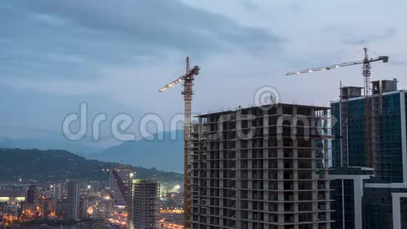 建筑施工从白天到晚上时光流逝建筑工地配备照明的塔式起重机视频的预览图