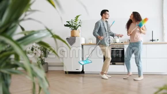 丈夫和妻子在厨房跳舞拿着拖把和掸子做家务视频的预览图