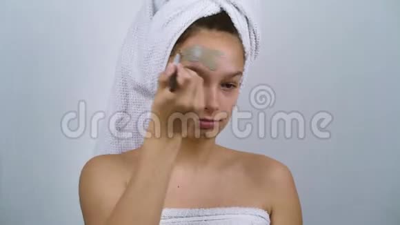 带着青春痘的少女用裹着脸上涂着黏土面具视频的预览图