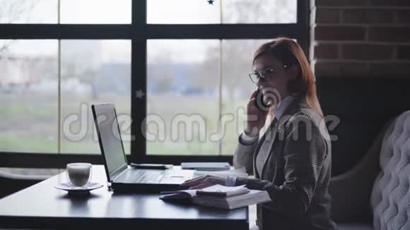 年轻漂亮的成功女性戴着眼镜与商业伙伴通电话观看工作报告视频的预览图