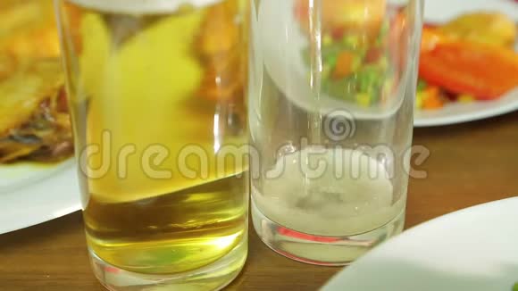 从瓶子里倒出的泡沫淡啤酒被倒入一个透明的玻璃杯中视频的预览图
