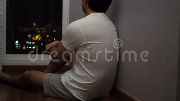 一个人坐在窗前看着沮丧和悲伤的夜晚视频的预览图