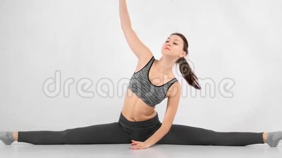 美丽的运动少女坐在细绳上转动纤细完美的身体伸展身体视频的预览图