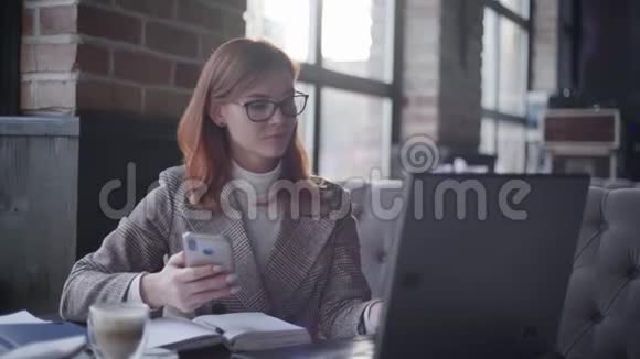 现代年轻漂亮的女企业家戴着眼镜手里拿着智能手机微笑着视频的预览图