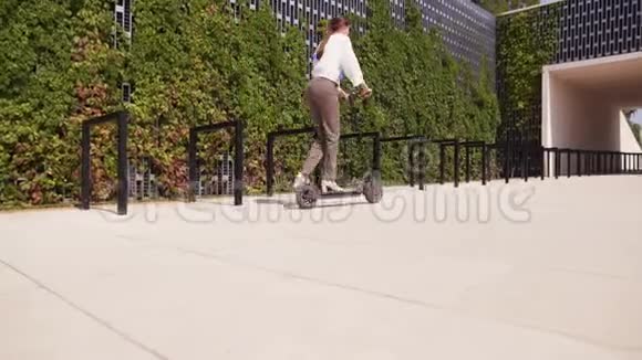 时髦的女商人在公园里推下水泥路面在午餐时间骑上电动滑板车视频的预览图