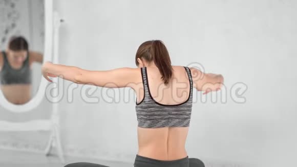 在瑜伽工作室后景女运动员在镜子前挥舞着手享受呼吸锻炼视频的预览图