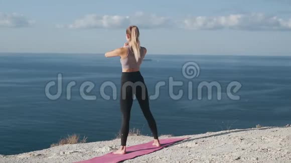 苗条的女人蹲在户外训练她的身体看海景慢动作视频的预览图