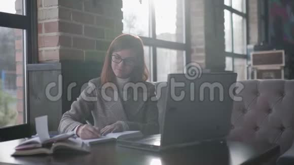 远距离学习成功的商务女性戴着眼镜正在网上学习一边在笔记本上做笔记视频的预览图