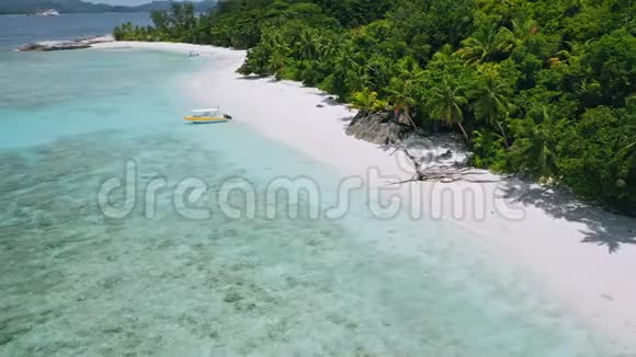 在热带异国海滩停泊的孤独旅游船的鸟瞰图蓝色泻湖清澈的蓝色海水和郁郁葱葱的视频的预览图