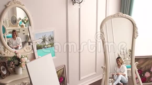 一个女孩在坐在地板上的卧室里画画它反射在镜子里视频的预览图