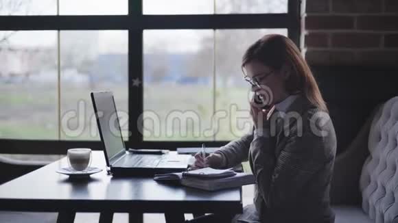 成功的商业女性戴着视力眼镜的女性在电脑和智能手机上工作因为接受了视频的预览图