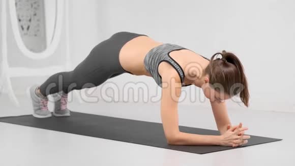 运动女性完美苗条的身体让腹肌在白色健身室的垫子上锻炼视频的预览图