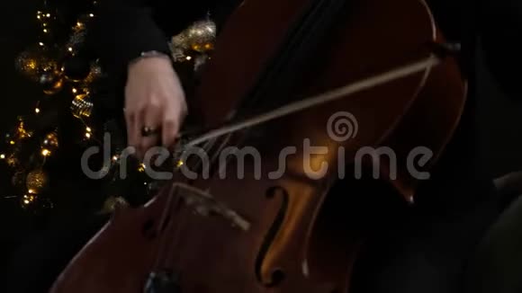 用大提琴演奏大提琴关闭男性手玩大提琴与大提琴弓古典乐团音乐视频的预览图