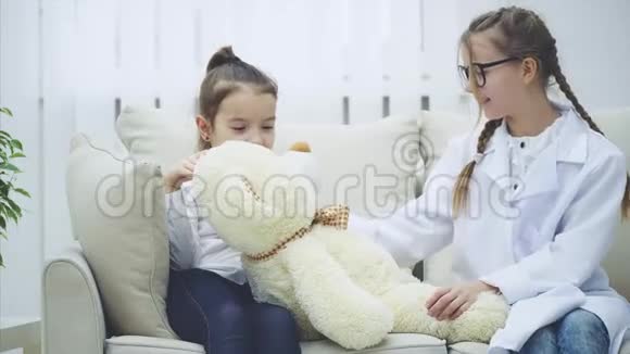 两个可爱的孩子在玩泰迪熊熊病了一个女孩是医生检查毛绒熊另一个女孩是熊视频的预览图