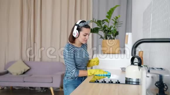 年轻女子穿着无线耳机洗厨房家具跳舞视频的预览图
