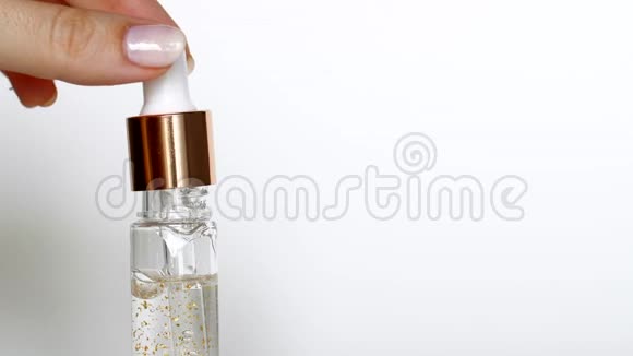 白色背景下从化妆品吸管中流出的滴金血清视频的预览图