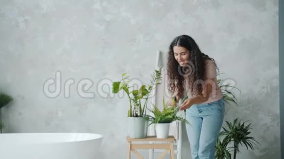 在家里用水喷洒植物的漂亮女士动作缓慢视频的预览图