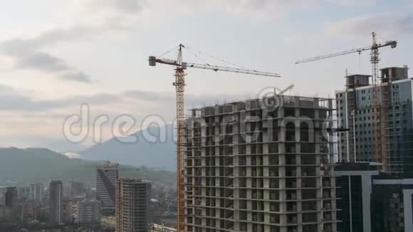 建筑工地上的塔式起重机在高层建筑中提升负荷时光流逝建筑工程视频的预览图