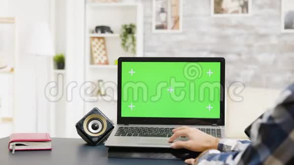 男人用绿色屏幕在笔记本电脑上的触摸板上滚动视频的预览图