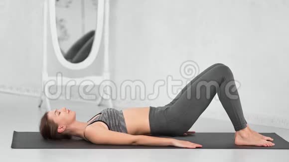 运动服装中的运动肌肉女性在白皮拉茨工作室内部的垫子上锻炼臀部肌肉视频的预览图