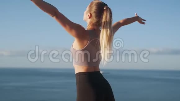 女性早晨练习瑜伽的背面视图背景的海洋慢动作视频的预览图