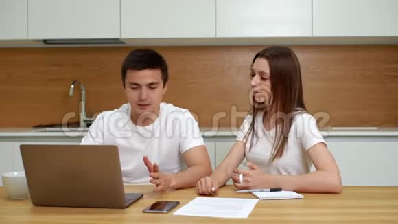 年轻夫妇用笔记本电脑坐在厨房里拥抱视频的预览图