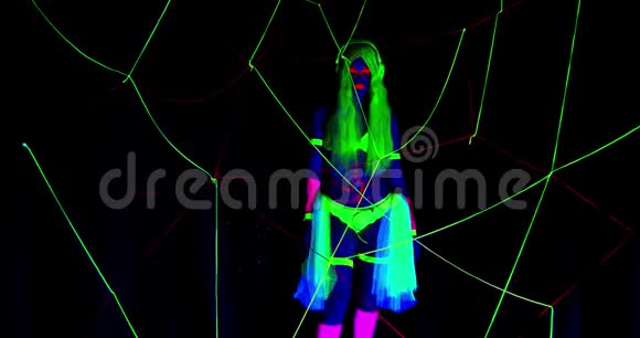 拥有紫外线身体艺术和化妆的女人在网后的黑暗中跳舞视频的预览图