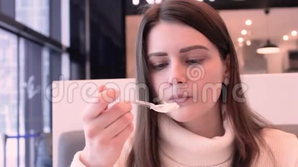 女人的手在咖啡馆里用白色毛衣的塑料勺子吃蛋糕视频的预览图