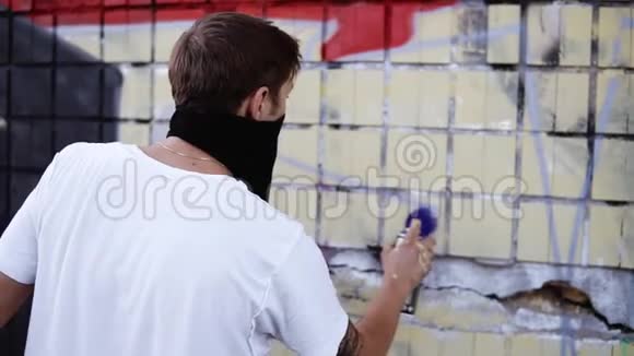 一个年轻人在工作过程中的特写在街道建筑墙上画一条蓝色的线条视频的预览图