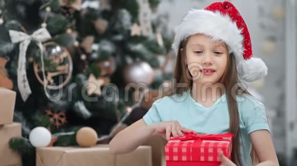 圣诞老人头顶礼品盒中一位惊讶女孩的特写肖像充满了积极的情感视频的预览图