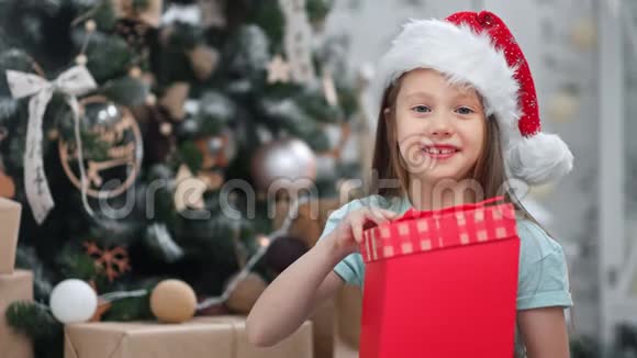 节日惊喜的脸可爱的孩子打开魔术圣诞礼物与红色丝带摆在装饰云杉视频的预览图